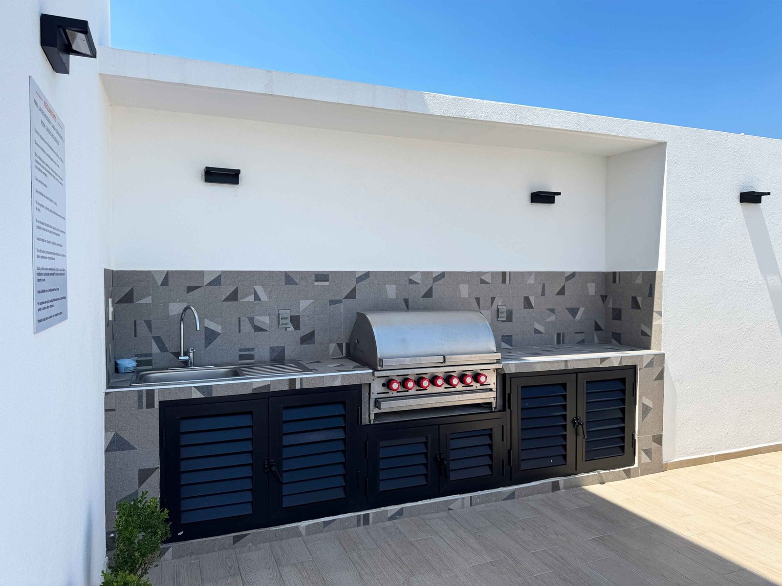 Área de grill profesional con acabados en piedra y barra de servicio en el roof garden de Antara.