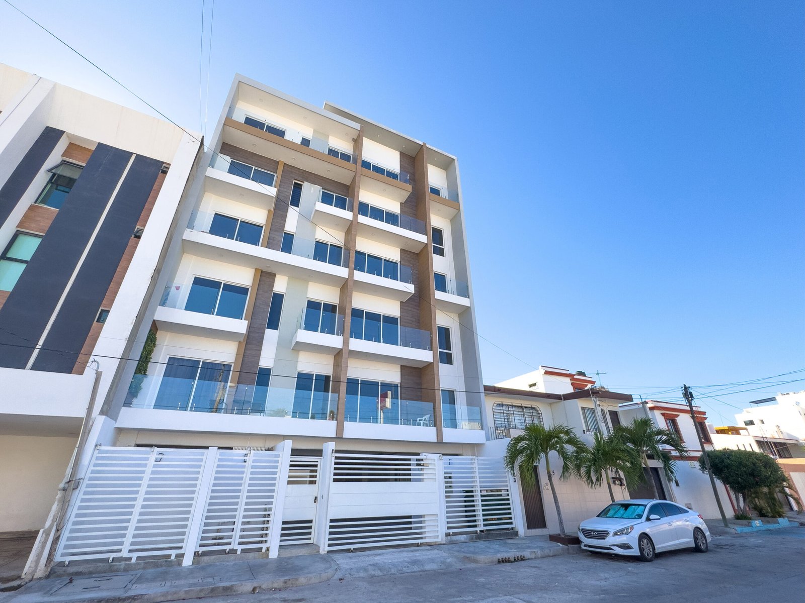 Perspectiva lateral de torre de departamentos residencial con acabados en madera y amplios ventanales.