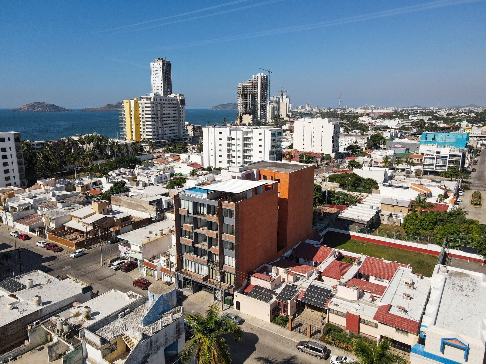 Vista aérea del edificio San Lorenzo mostrando su arquitectura moderna y cercanía al mar en Mazatlán.