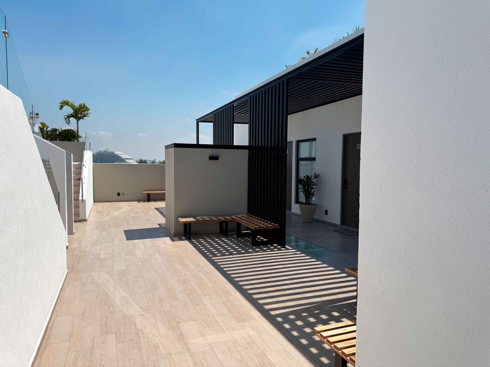 Pasillo exterior con diseño contemporáneo, pérgolas de madera y acabados minimalistas en Antara.