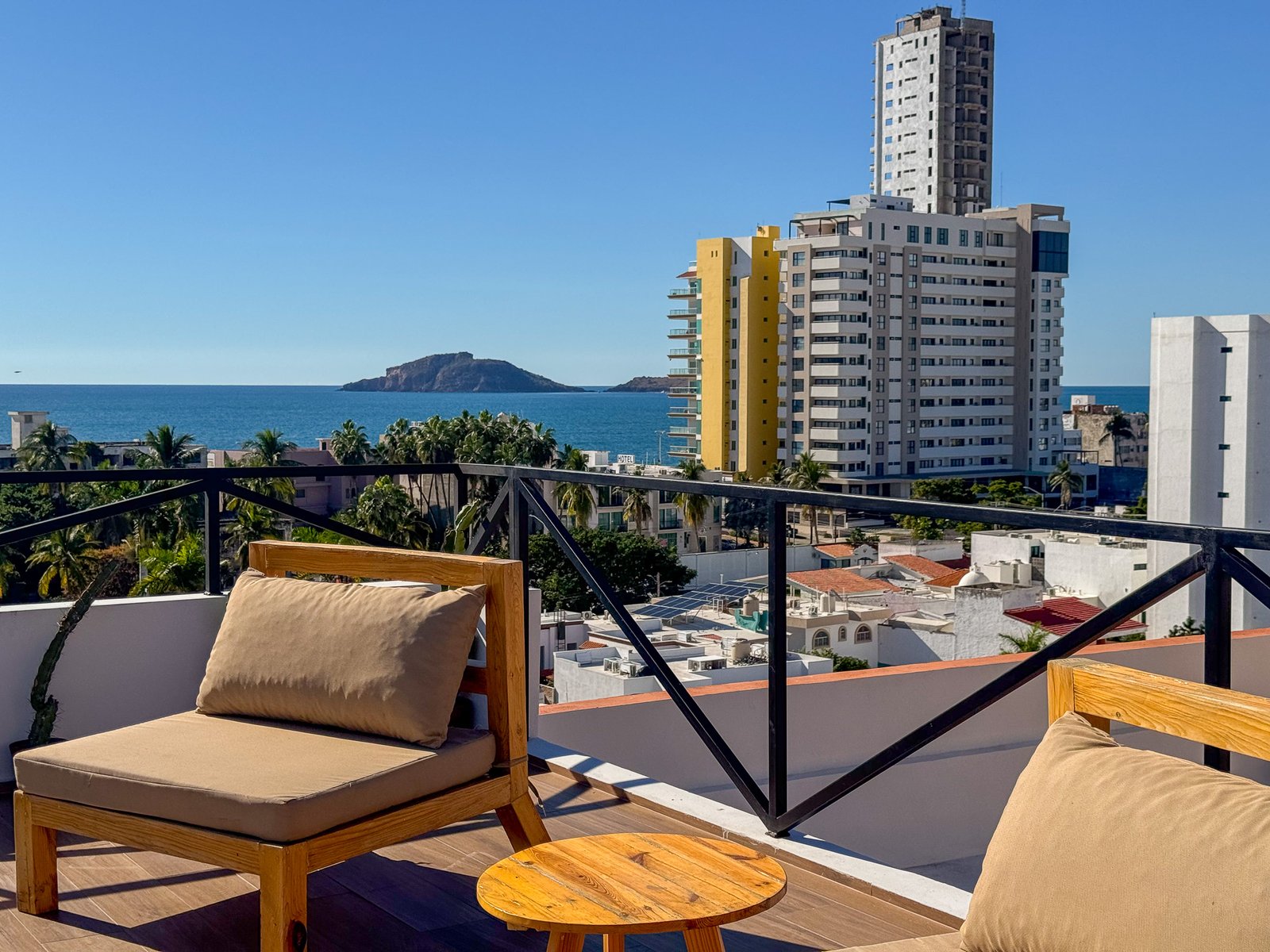 Camastros modernos de madera en el área de alberca con vista a las islas de Mazatlán.