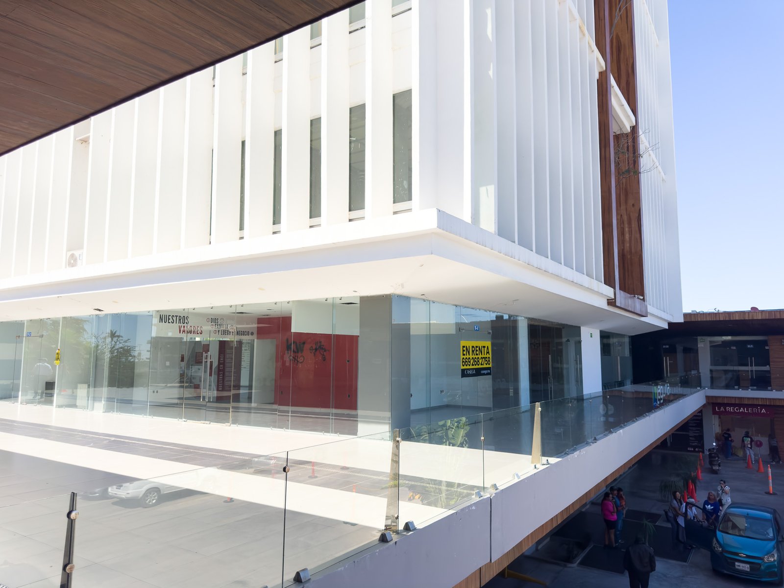 Entrada principal del local comercial F1 con amplios ventanales y acceso desde la terraza.