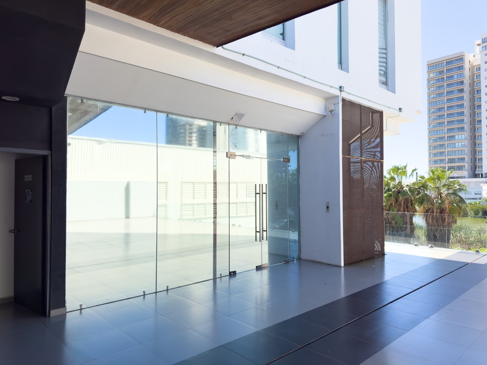 Fachada moderna de local comercial con ventanales de piso a techo y acceso principal en cristal templado.