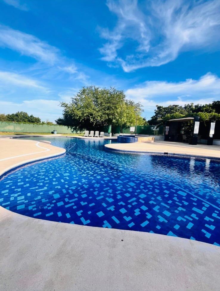 Vista panorámica de la alberca de diseño curvo y aguas cristalinas en el resort Manzara.