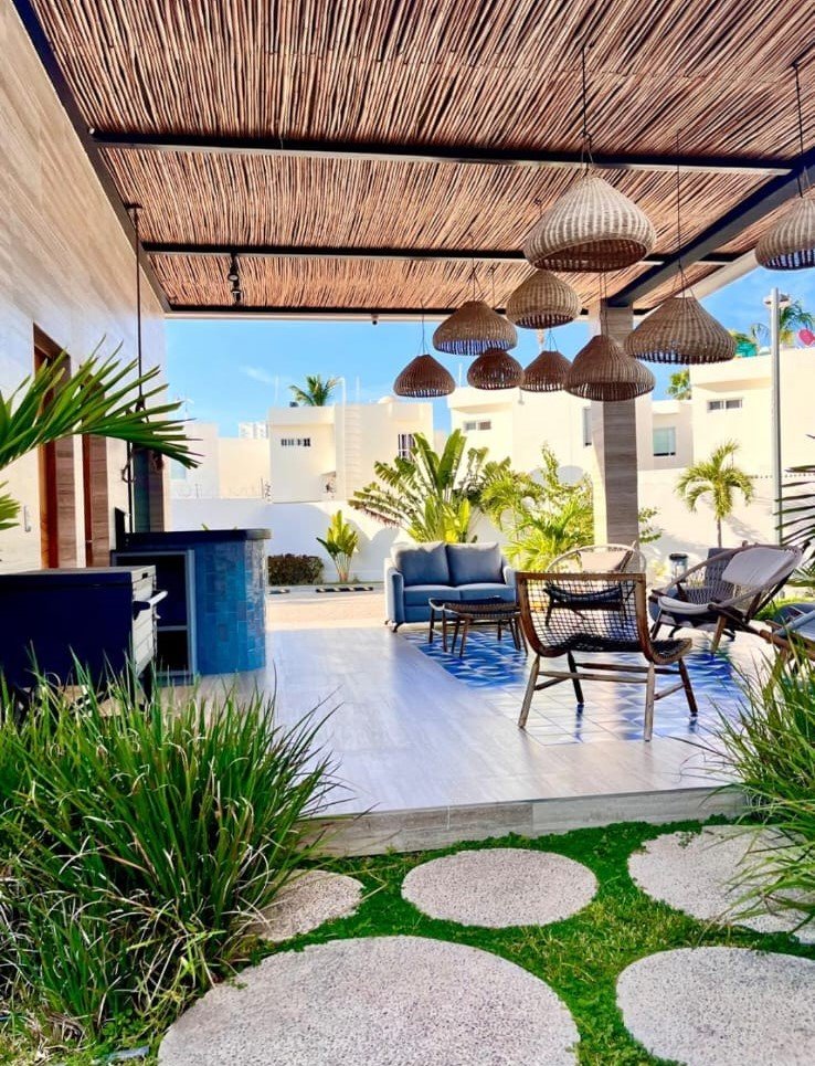 Sala de exterior decorada con estilo boho-chic, muebles de diseño y vista a las áreas comunes del resort.