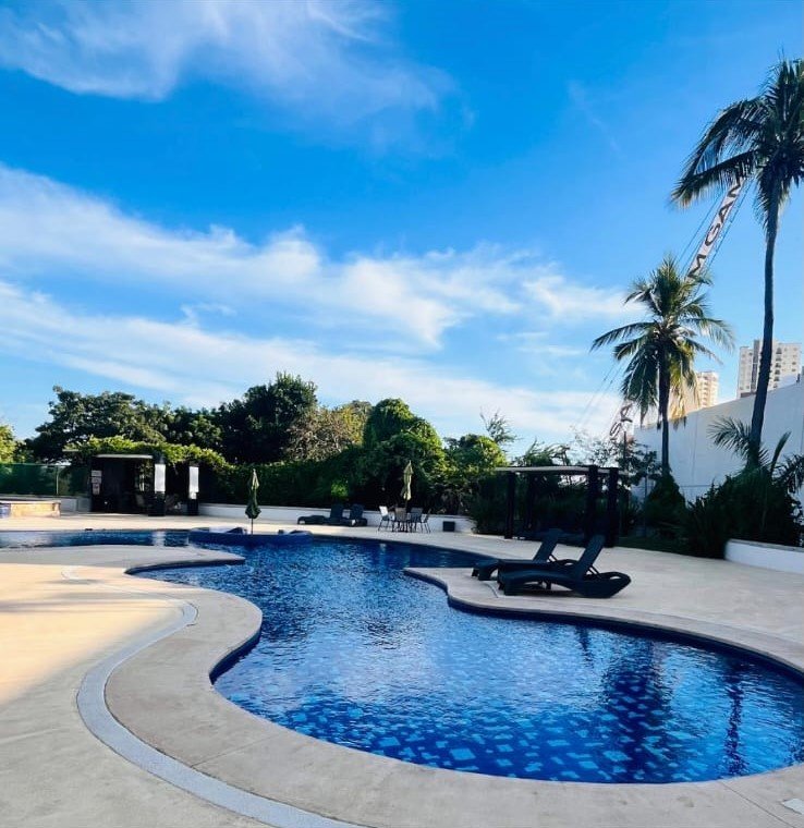 Amplia alberca con acabados en mosaico azul bajo un cielo despejado en Manzara.