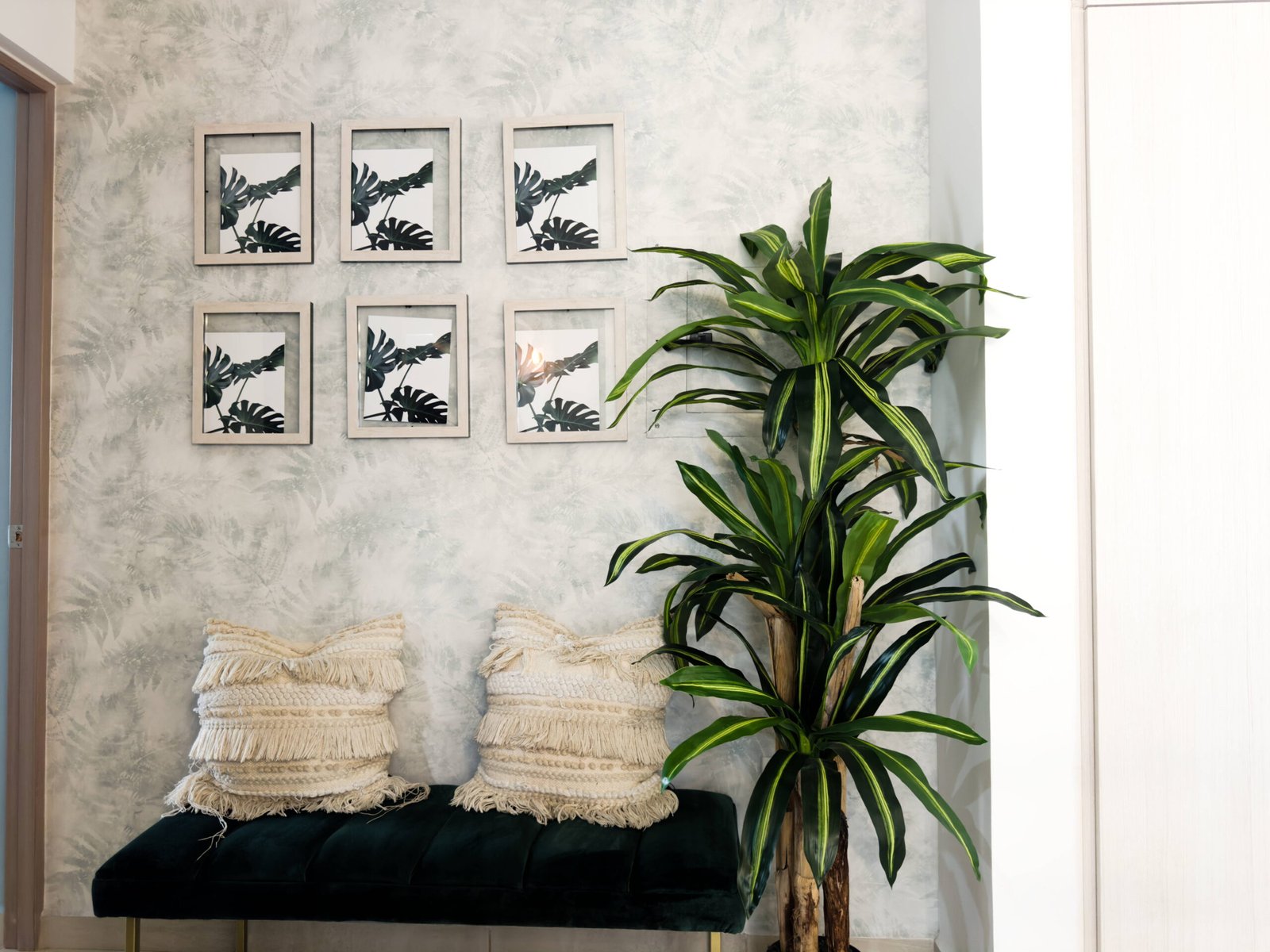 Banco de terciopelo verde con cojines bohemios y planta ornamental en el interior de Almarena 1314.