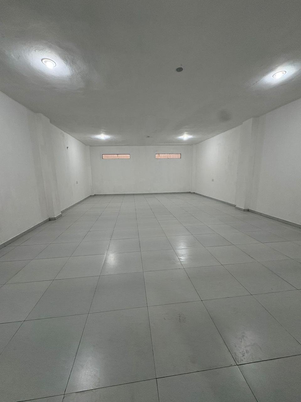 Gran salón en planta alta con piso cerámico y ventanales de ventilación superior.